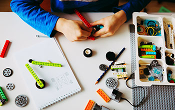 Hands using Lego bricks to build robotic vehicle
