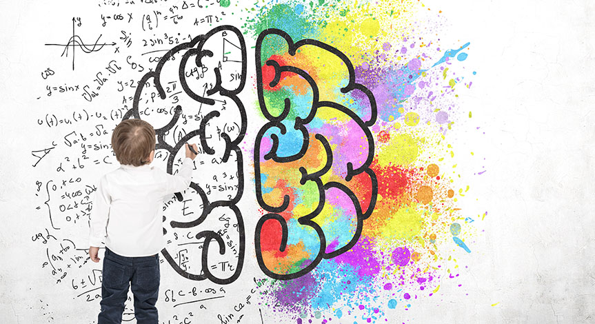 Boy writing formulas on a white wall with a brain and color splashes on it.