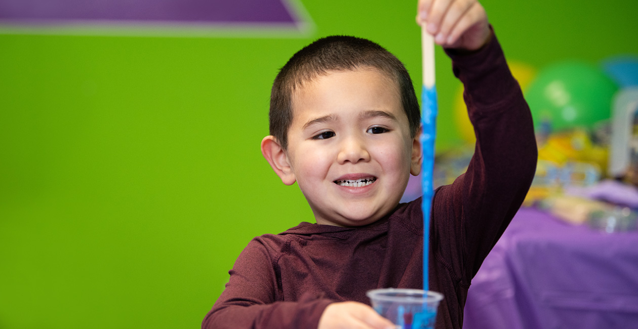 Boy playing with slime in an Activity Cup that he made at a birthday party.